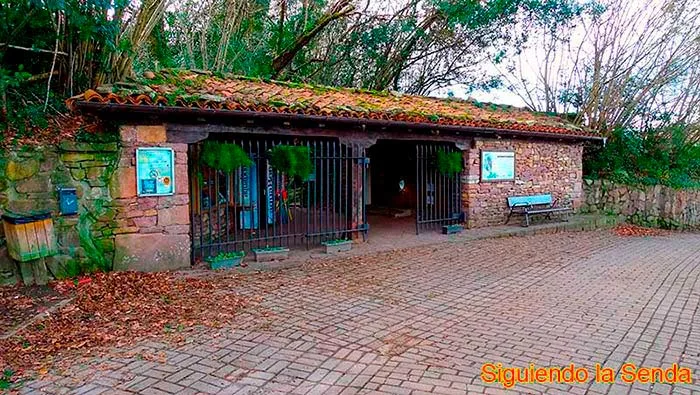 Entrada principal al recinto de las Cuevas de Zugarramurdi, con un cartel de madera y un camino de piedra.