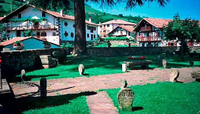 Iglesia de Etxalar rodeada de sus características estelas discoidales de piedra.