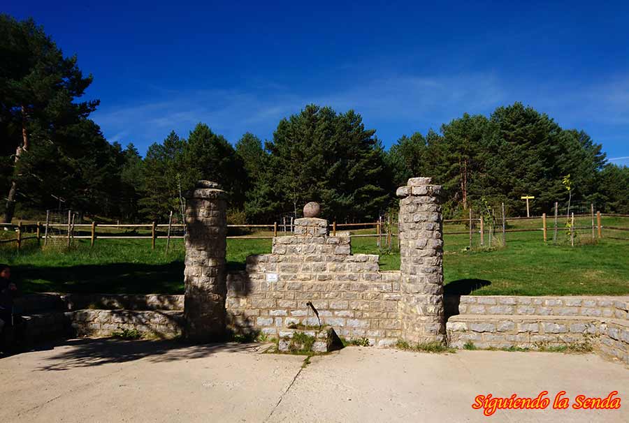 Sumérgete en la Belleza de la Laguna de Noguera: Un Lugar Único 12 Fuente del Ojuelo, una construcción de piedra rústica con un caño de agua del que brota un chorro, rodeada de vegetación.